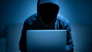 Hacker in Dunkelheit vor einem Laptop (verweist auf: Anonyme Hinweise an die BLE richten)
